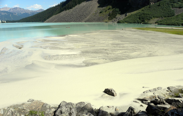 The water of Lake Louise has a pastel emerald color because it is loaded with very fine sediment called "glacial flour". It is produced by glacial ice finely grinding the rocks in the highlands above. This sediment fills the streams to near capacity and makes an extensive delta at the inlet to the lake.